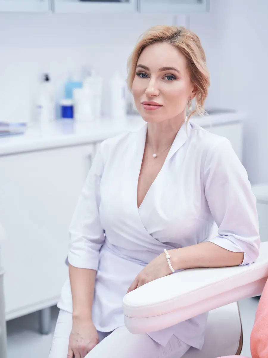 A esteticista do Studio Lume na sala de tratamento, sentada junto à marquesa.
